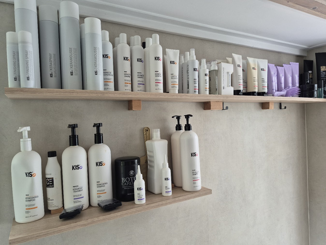 Interieur van Haarmode Verheijen met spiegelwand, werkplekken en warme houttinten.